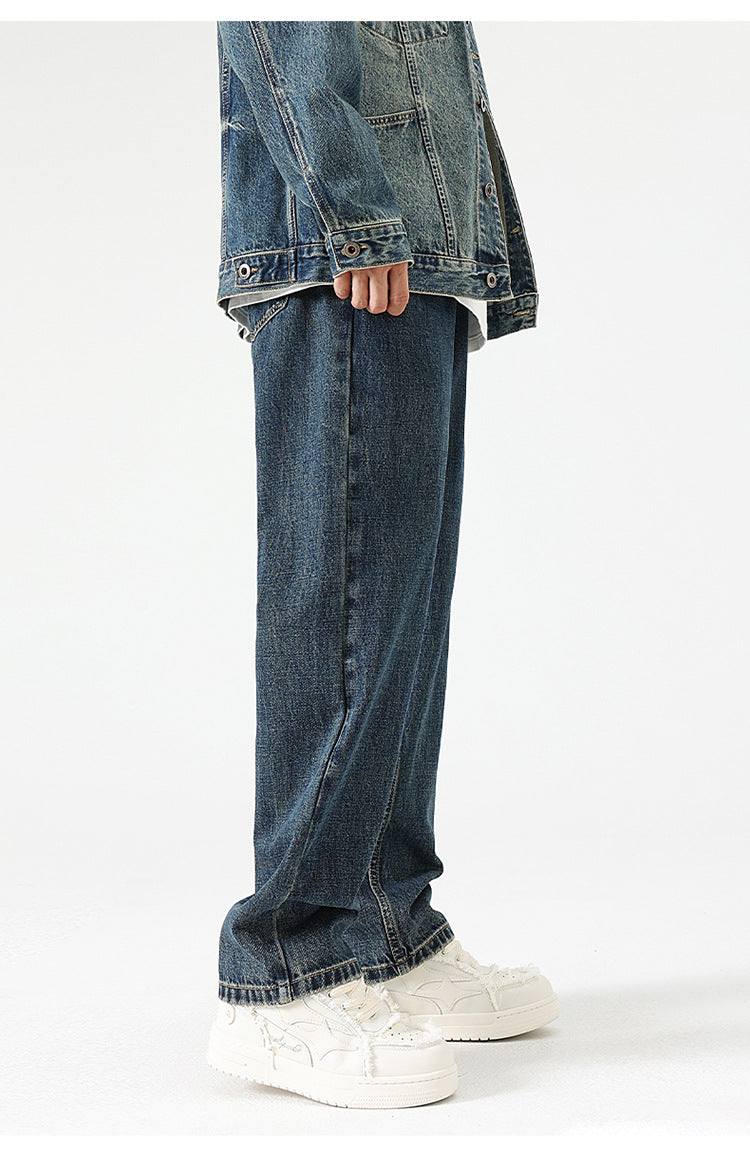 A model is standing wearing oversized straight-cut denim jeans with a denim jacket, showcasing the relaxed silhouette against white