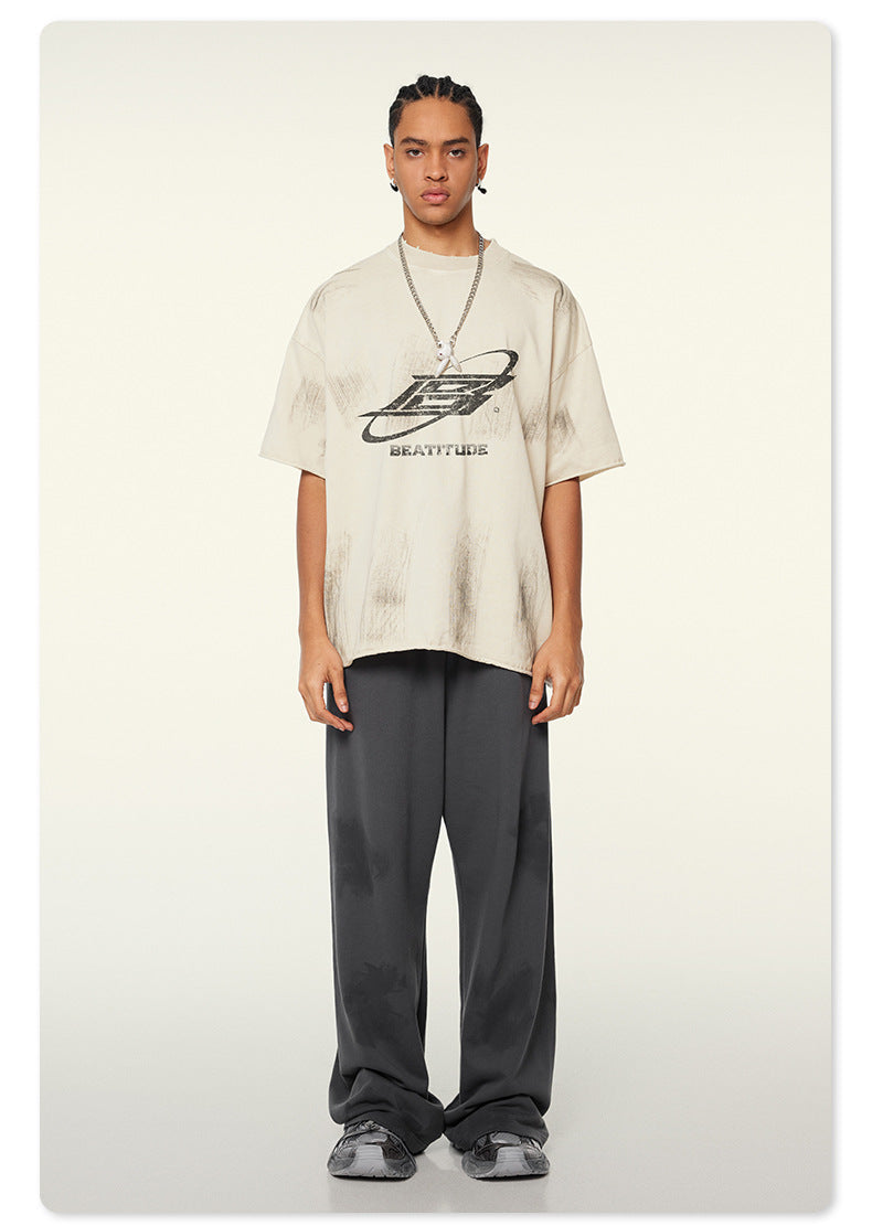 Oversized off-white Beattube t-shirt with distressed logo, wide gray pants, and gray sneakers