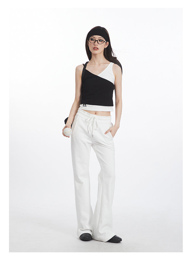 Two-piece athletic set with black and white asymmetric crop top and white flared pants