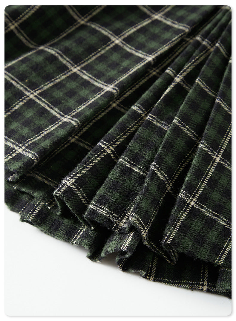 Close-up of green plaid fabric folds showing texture and pattern detail against dark background