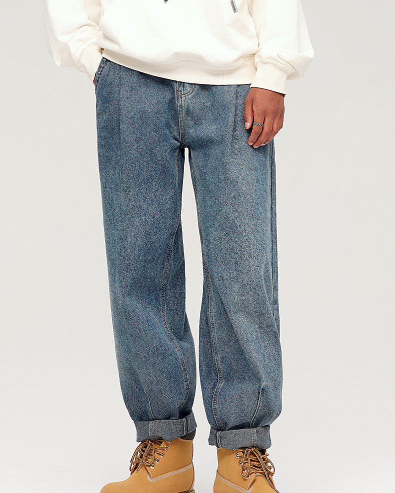 A model wearing wide-leg medium-wash jeans with cuffed hems, white hoodie and tan work boots, standing against white background