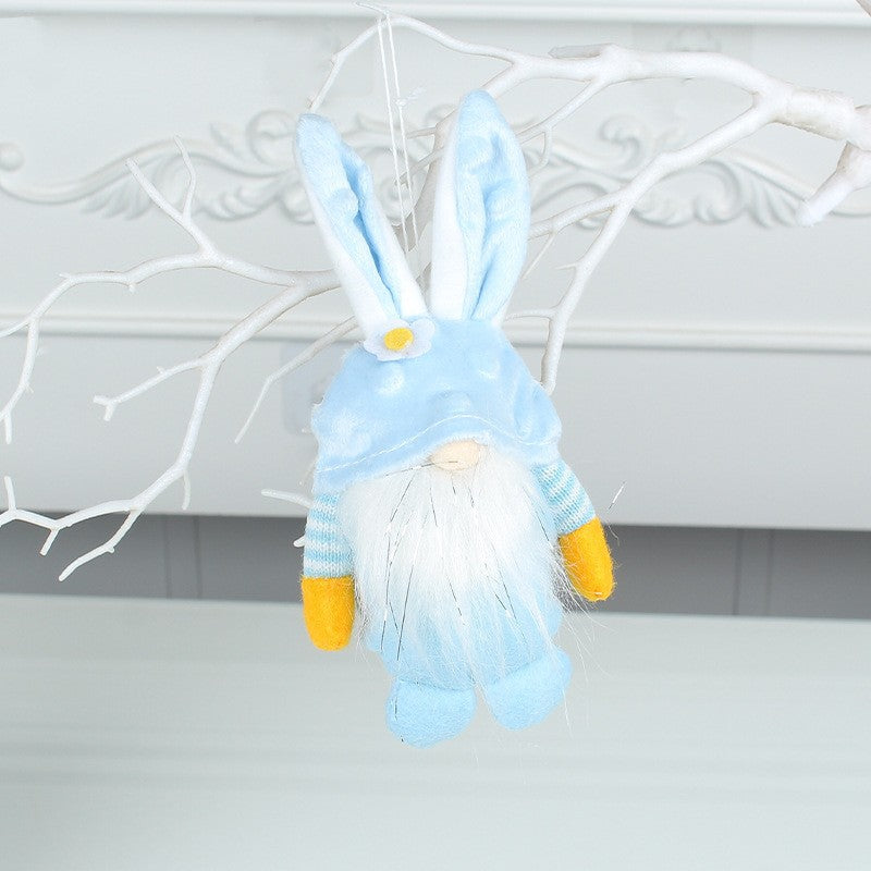 Blue plush bunny gnome with flower detail, hanging on a decorative white branch with a soft beard and striped sleeves.