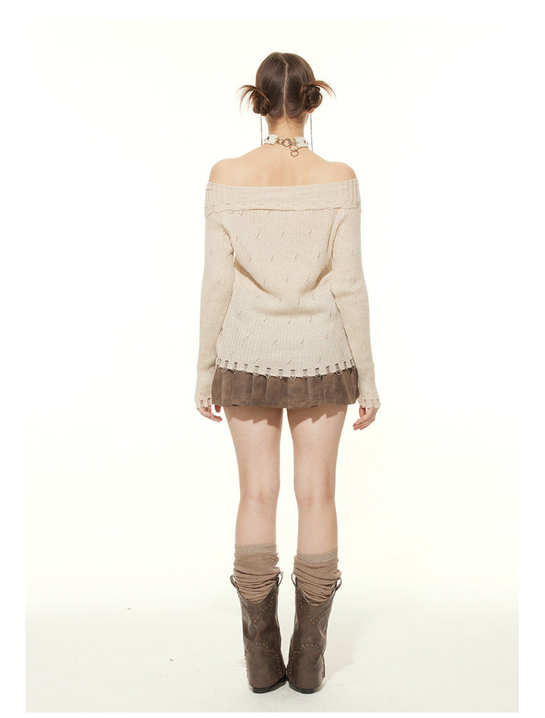 Back view of cream ribbed sweater showing off-shoulder neckline and distressed hem detail, worn with brown pleated skirt and tall brown boots with gathered socks