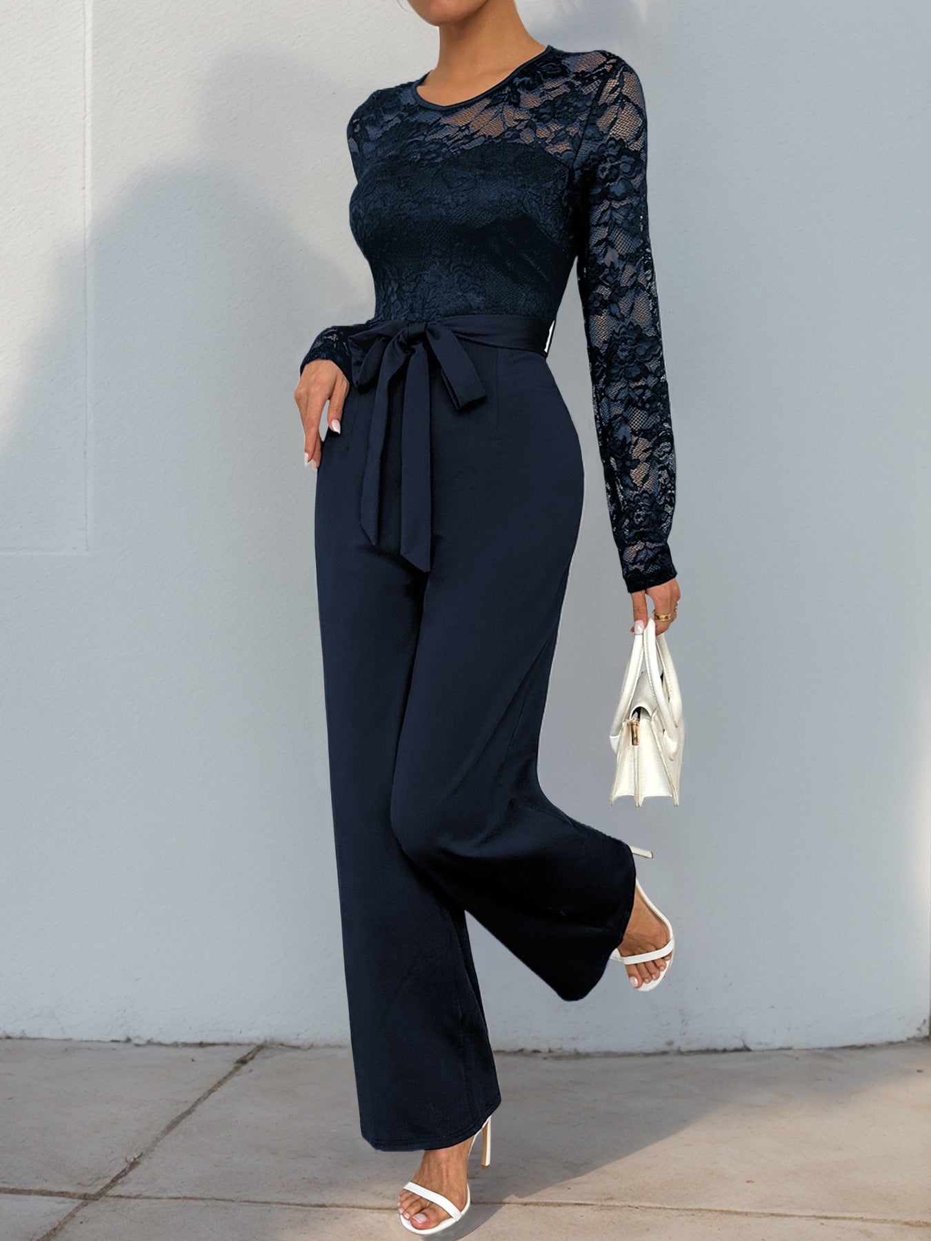 Side angle of the navy blue lace jumpsuit, showcasing the sleek fit and belted waist.