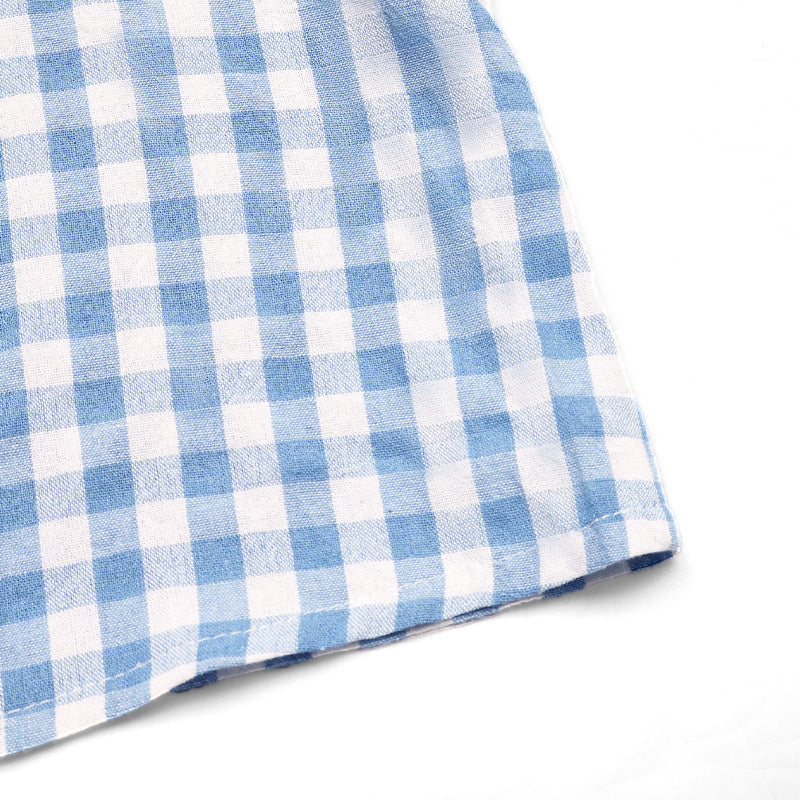 Hem detail of the blue gingham top, focusing on the clean stitching and lightweight fabric.