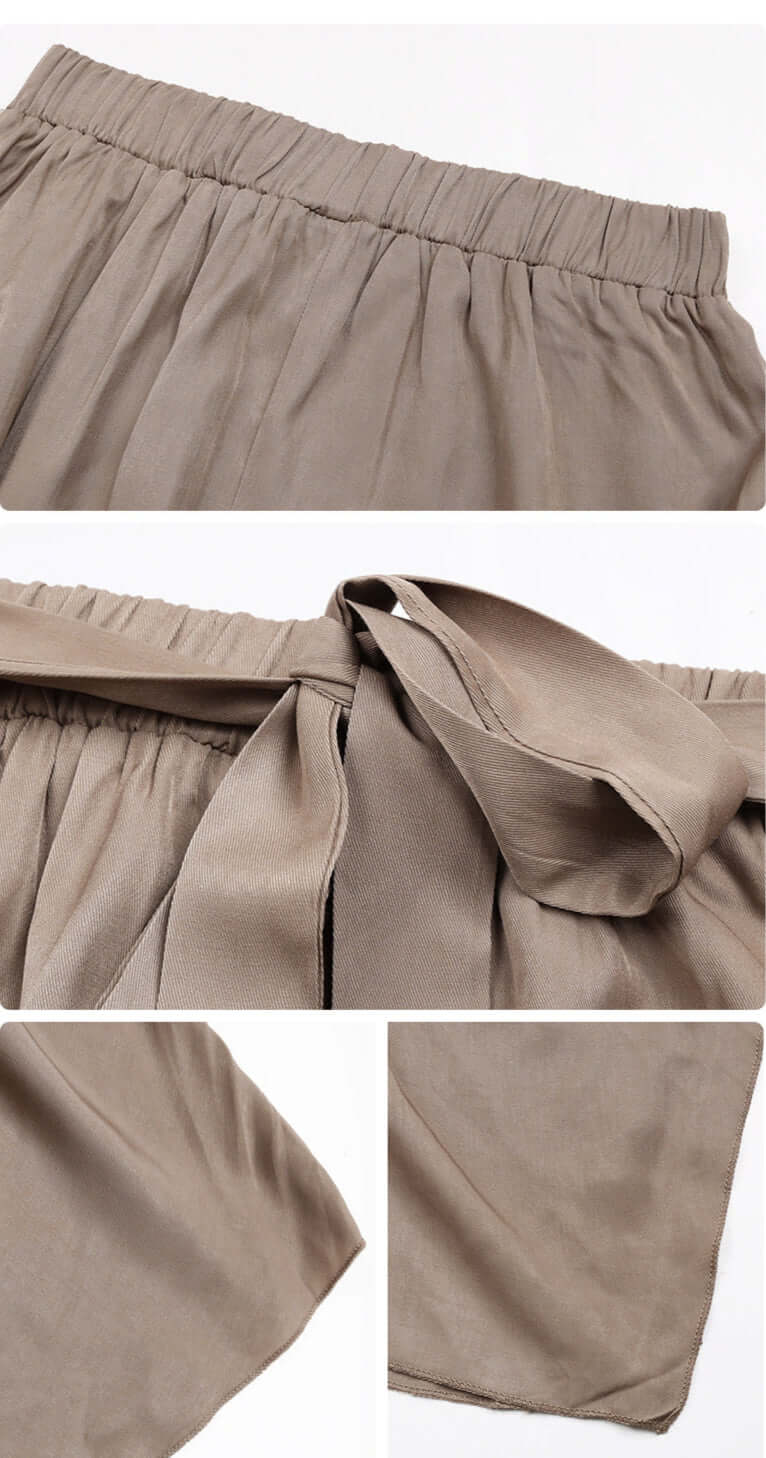 Detail shot of the waistband and tie of a khaki asymmetrical midi skirt, showing its soft, gathered fabric.