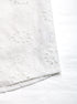 Hemline close-up of white embroidered blouse, showing floral cutout pattern and scalloped edges.