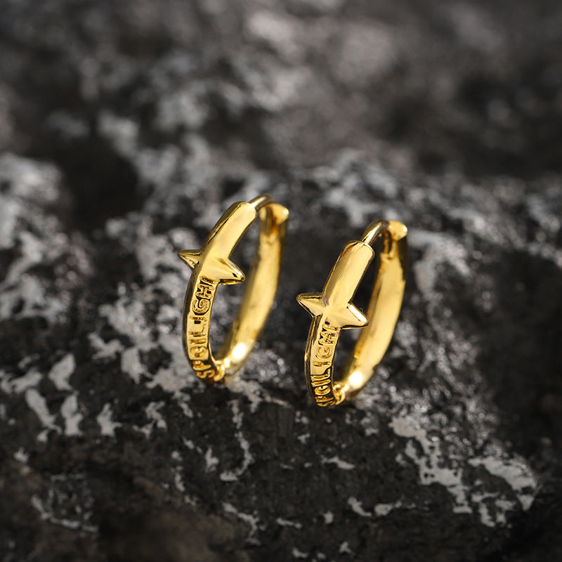 Gold color star hoop earrings on dark stone texture