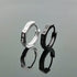 Silver and black silver hoop earrings with Roman numeral engravings, shown with reflection