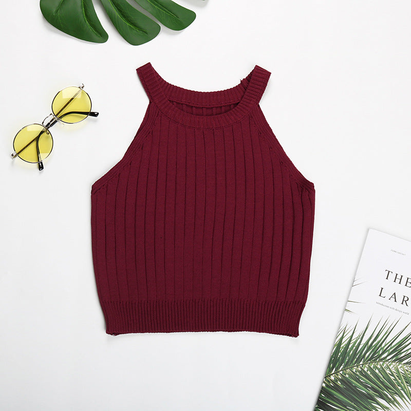 Burgundy ribbed halter crop top flatlay with yellow sunglasses and tropical decor