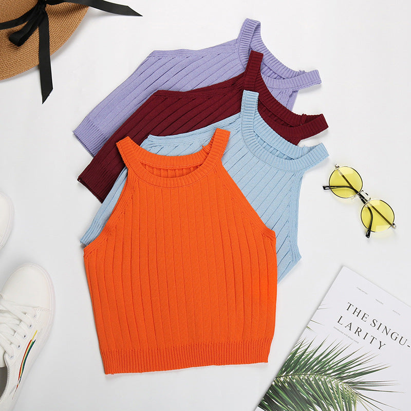 Flatlay of four ribbed halter crop tops in orange, burgundy, lavender and light blue, styled with sunglasses and book
