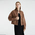 Coffee-toned denim jacket with chest pockets, model in black fitted dress, studio setting