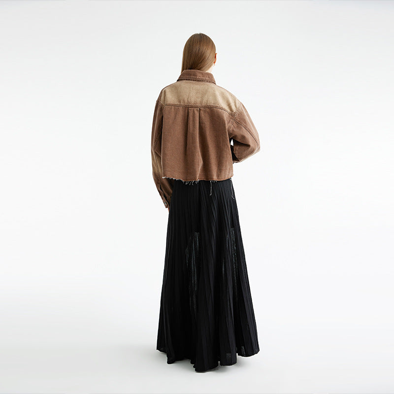 Back view of brown denim jacket with black pleated maxi skirt, neutral background