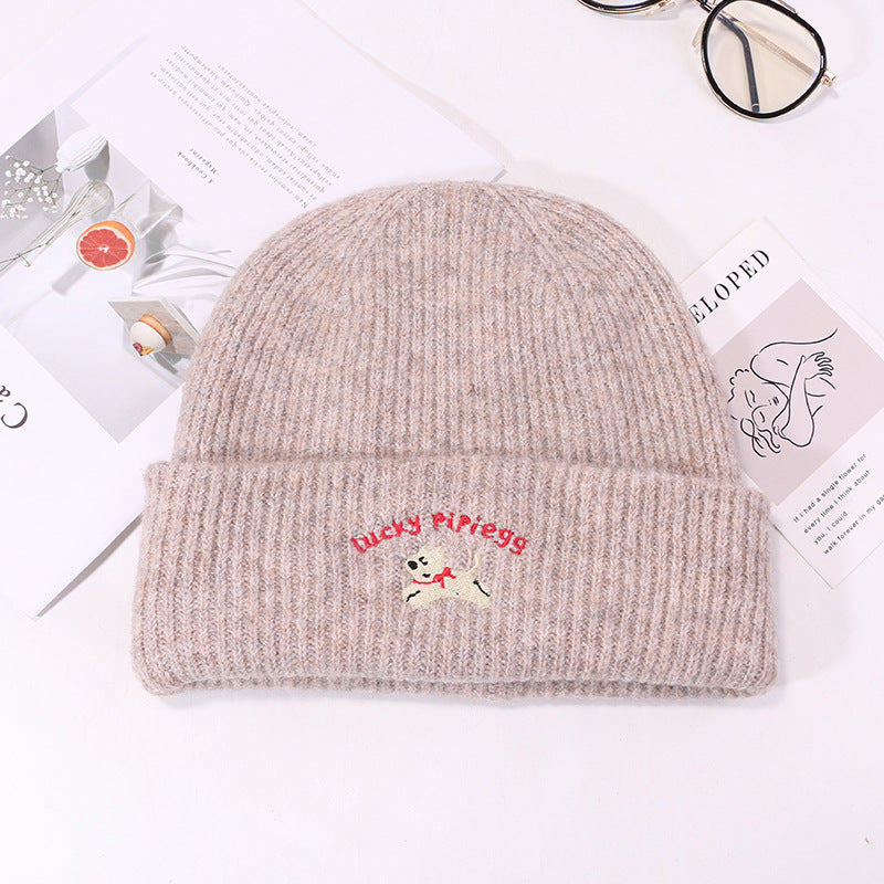 Beige ribbed knit beanie with embroidered puppy logo on product display