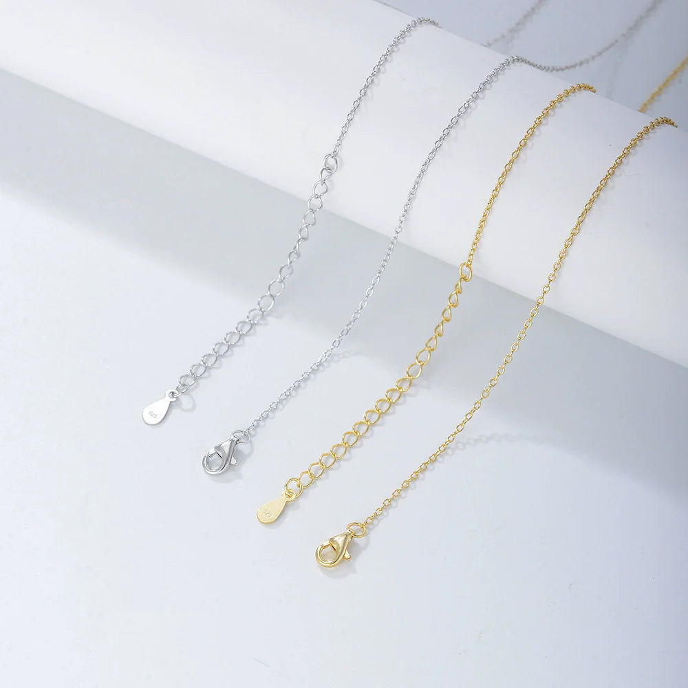 Silver and gold chain options with extension clasps displayed on white surface, showing different lengths and attachment mechanisms