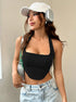 Woman wearing black ribbed halter crop top with light wash jeans, white baseball cap and silver headphones