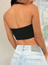 Back view of black ribbed halter crop top with contour seams, paired with light wash denim