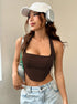Woman in chocolate brown ribbed halter crop top styled with baseball cap and silver headphones