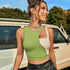 Woman wearing green and white crop top, silver jewelry and black leather shorts in front of vintage car