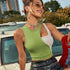 Close-up of woman smiling in green crop top, brown sunglasses, and silver chain accessories outdoors