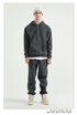 Male model wearing dark gray sweatsuit and white beanie hat, photographed against white background