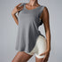 A woman is wearing a gray sleeveless relaxed-fit tank top with cream shorts, touching her collarbone against a neutral background