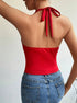 A woman is shown from behind wearing a red tie-neck bodysuit with an open back design and ribbon closure, paired with blue denim jeans