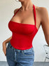 A woman is standing in a red halter neck bodysuit with molded cup design, styled with medium-wash denim jeans