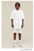 Man wearing white oversized T-shirt and shorts set with silver chain necklace and white sneakers