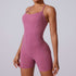 A model wearing dusty rose bodysuit with contoured seams and built-in shorts, photographed against light gray backdrop