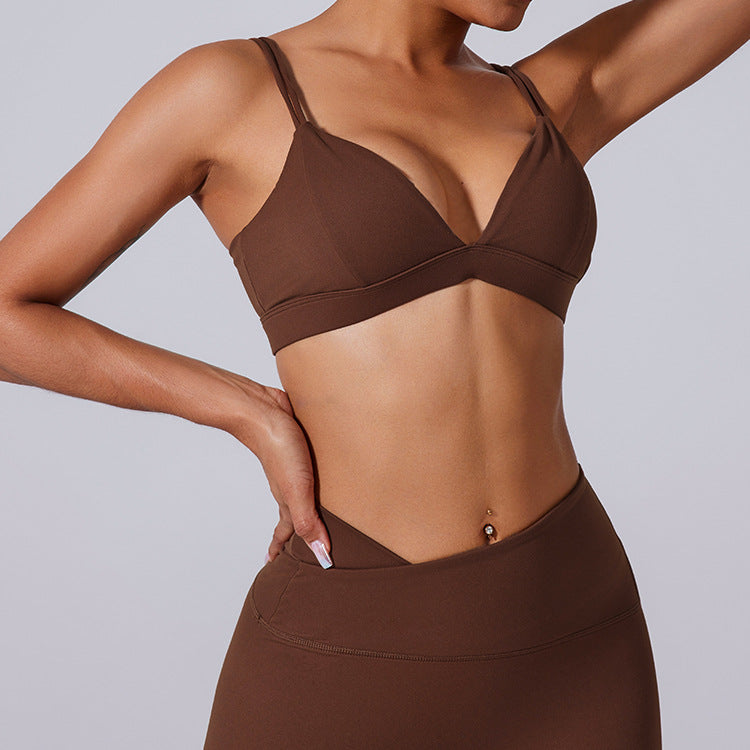 Woman in brown triangle bralette sports bra with dual straps and high-waisted leggings, hand on hip