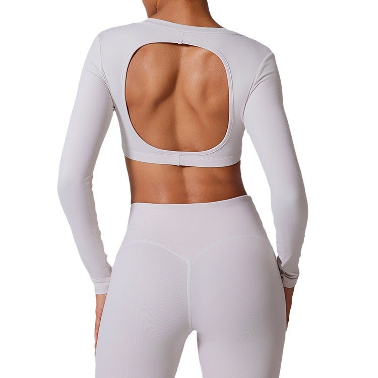 Back view of white long sleeve crop top with large open cutout and high-waisted leggings