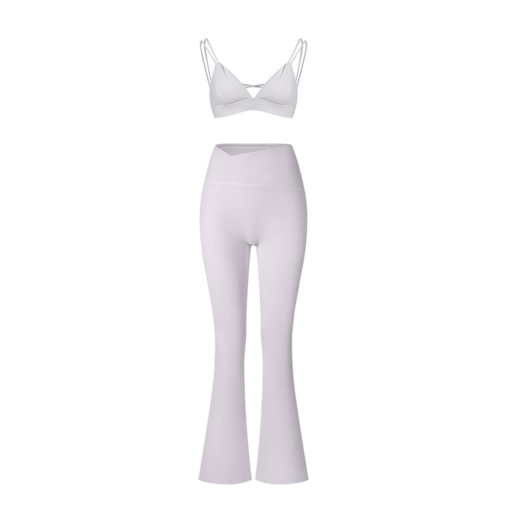 White strappy sports bra with dual shoulder straps and high-waisted flared yoga pants against white background