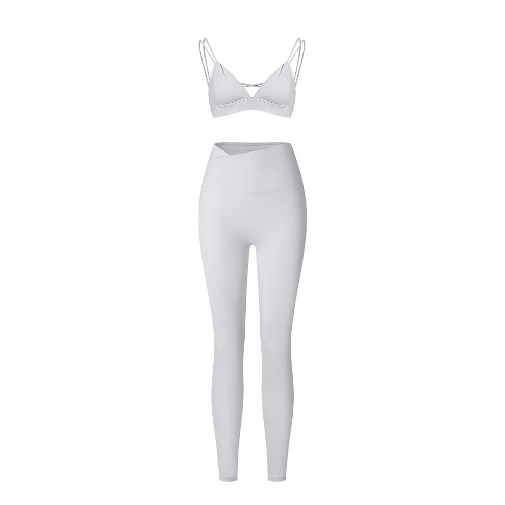 White strappy triangle bralette and high-waisted leggings set with asymmetrical waistband on white background