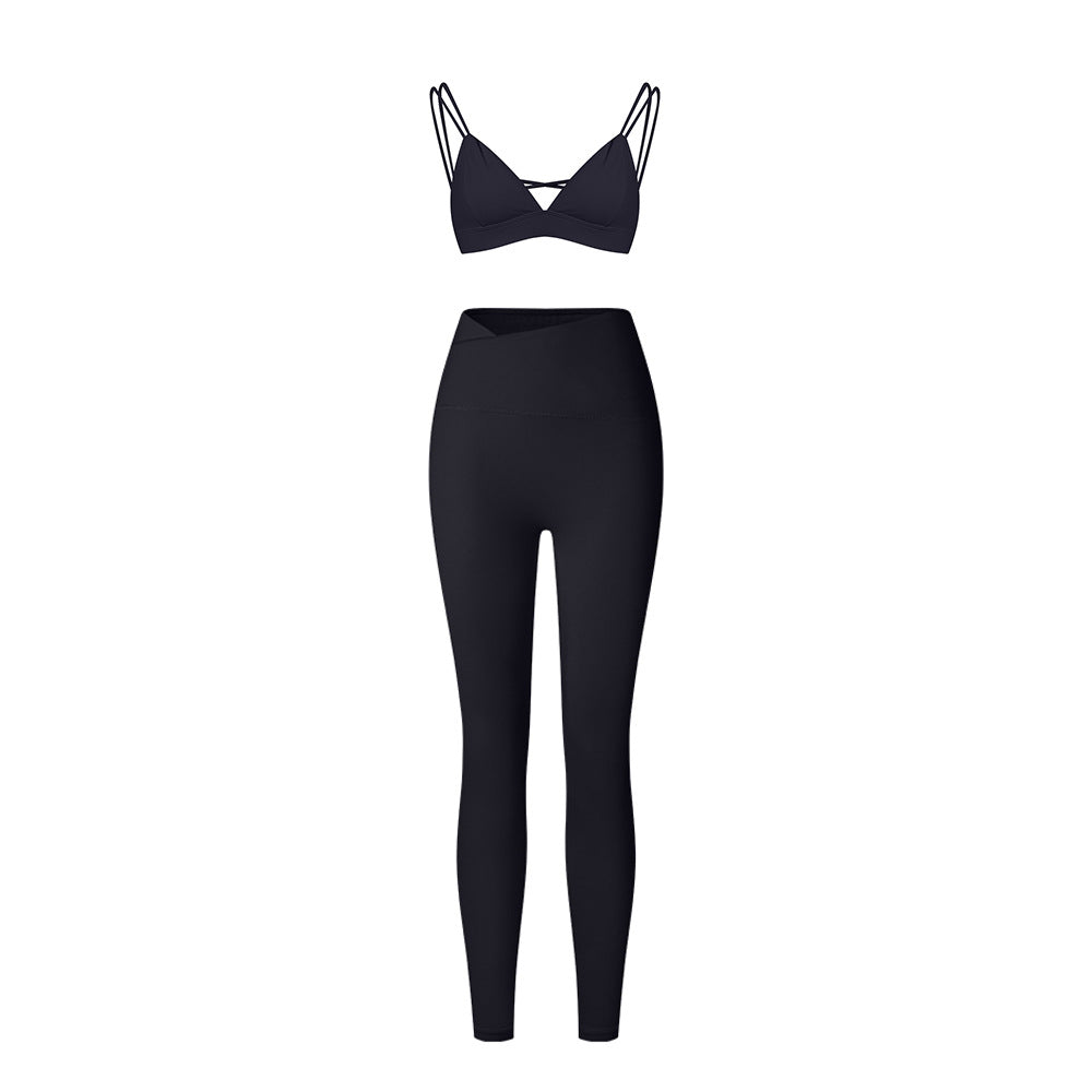 Black strappy triangle bralette and high-waisted leggings set with asymmetrical waistband on white background