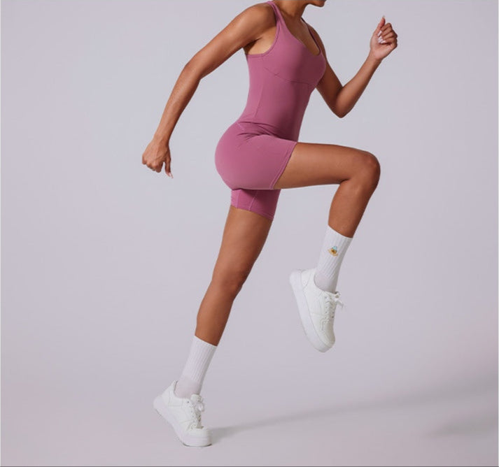 Model jumping in mauve pink sleeveless bodysuit showing athletic fit and movement, paired with white socks and sneakers