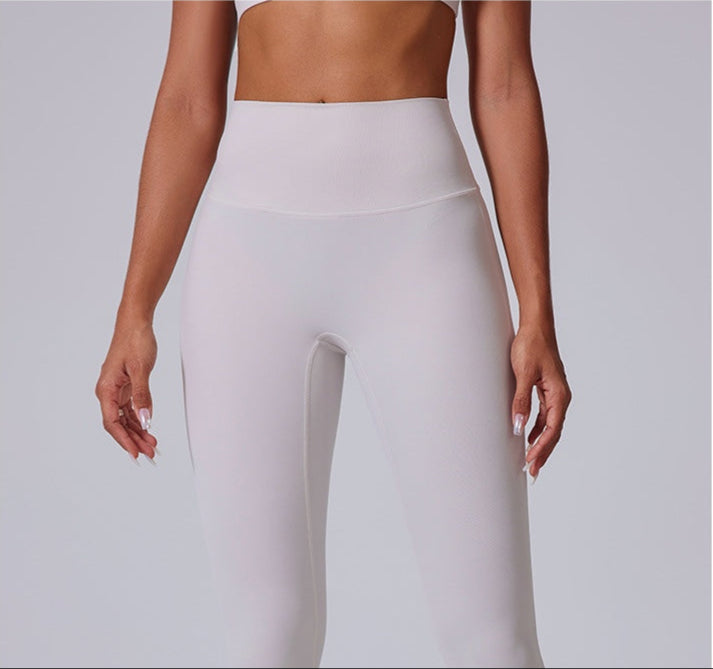 A woman wearing white high-waisted athletic leggings with a wide waistband, shown from the front with hands at sides against a gray background