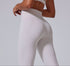 A woman wearing white high-waisted athletic leggings with contoured seams, photographed from behind in a side-angled pose against a gray background