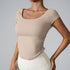 Model wearing nude square-neck crop top with side ruching and cream leggings, photographed against gray background