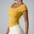 Model in mustard yellow square-neck crop top with ruched sides and cream leggings against minimalist gray backdrop