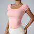 Model wearing soft pink square-neck crop top with side ruching and cream leggings against gray background