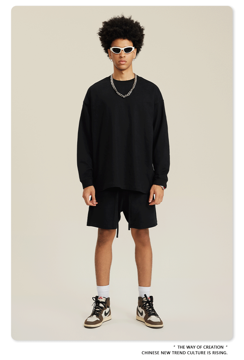 Man in black sweatshirt and shorts set with white sunglasses, chain necklace and sneakers