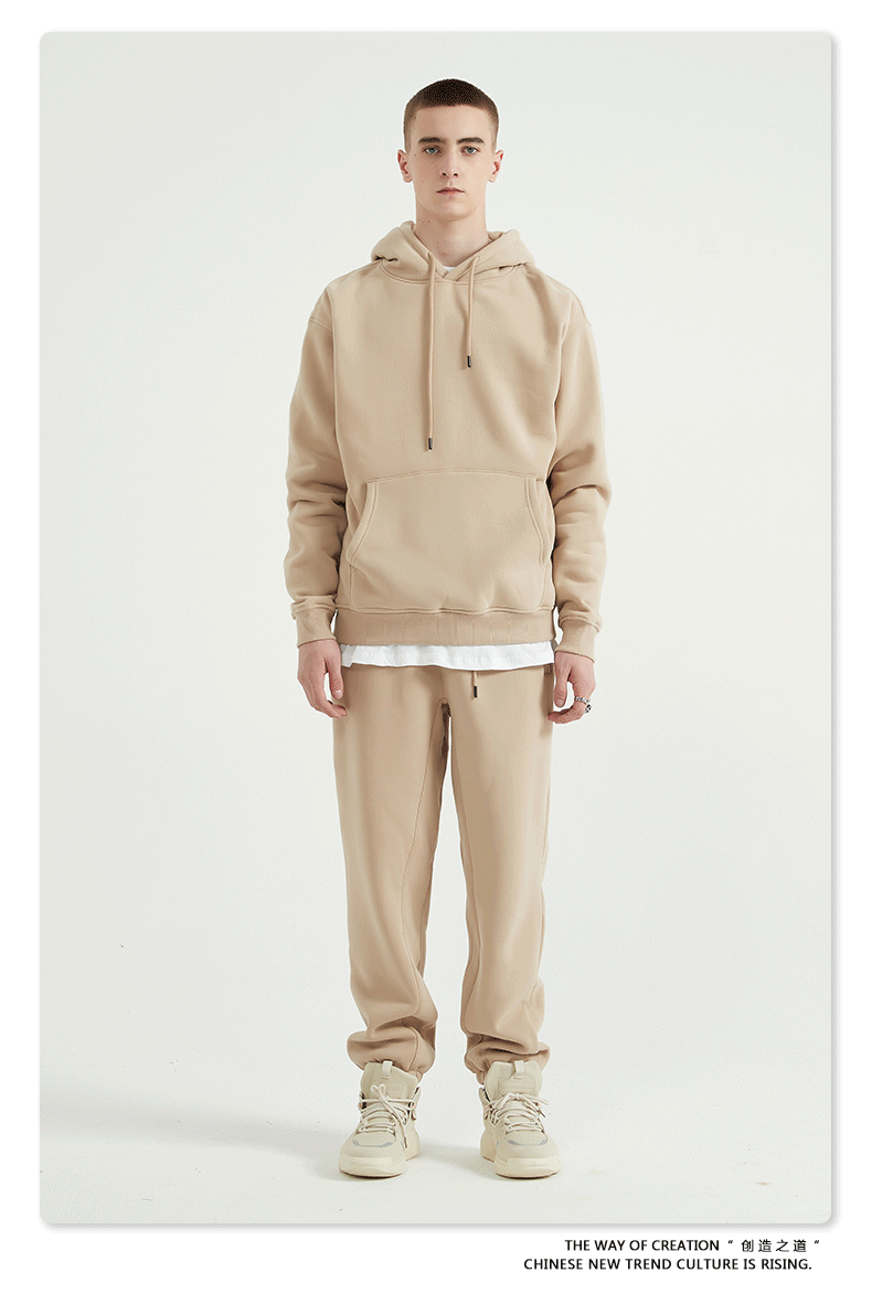 Male model with short hair wearing a beige sweatsuit with hoodie, white undershirt, and matching joggers
