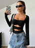 Woman wearing a black cutout bodysuit styled with a statement denim maxi skirt, accessorized with sunglasses and a silver bag.