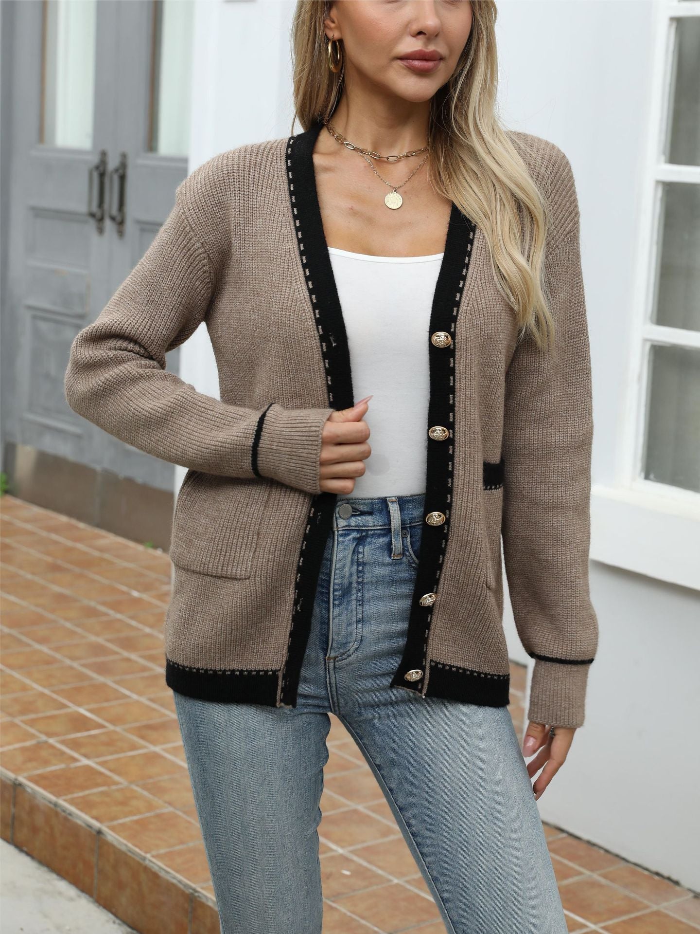 Beige knit cardigan with black trim, worn with white tank top, gold sunglasses, and necklace