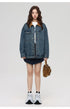 Woman in blue denim jacket with brown corduroy collar over graphic tee and navy skirt with brown handbag