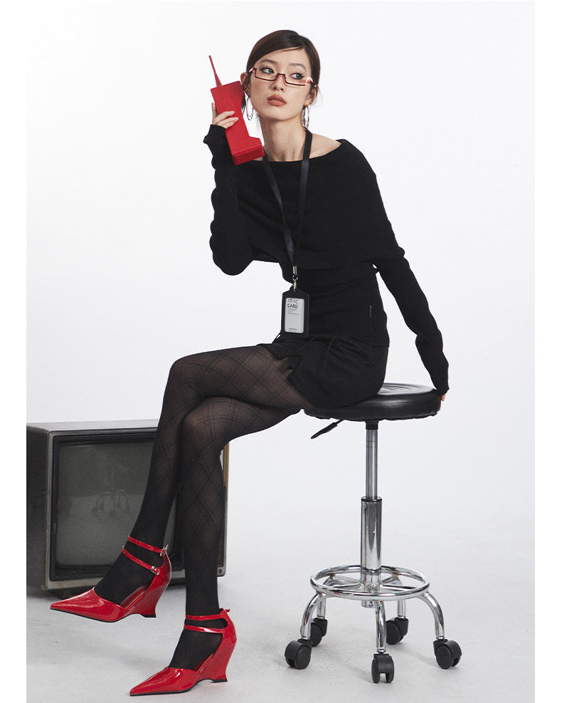 Black off-shoulder sweater with fold-over neckline and fitted sleeves, styled with ID lanyard. Side sitting view.