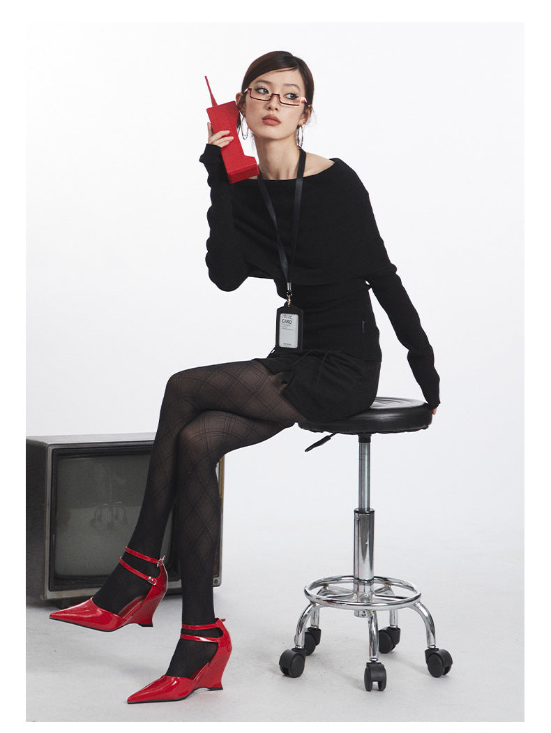 Black off-shoulder sweater with fold-over neckline and fitted sleeves, styled with ID lanyard. Side sitting view.