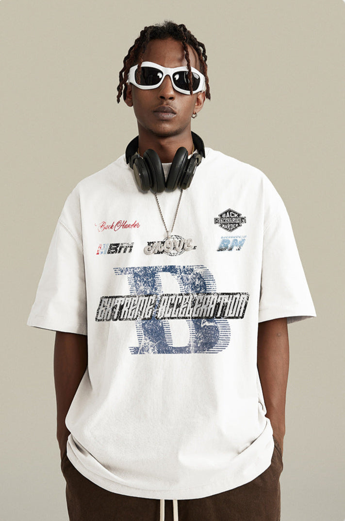 A model wearing white oversized t-shirt with street graphics, white-framed sunglasses and black headphones around neck against neutral backdrop