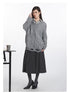 Angled view of grey V-neck sweater highlighting cable-knit pattern and intentionally distressed edges, styled with midi skirt and striped shirt collar